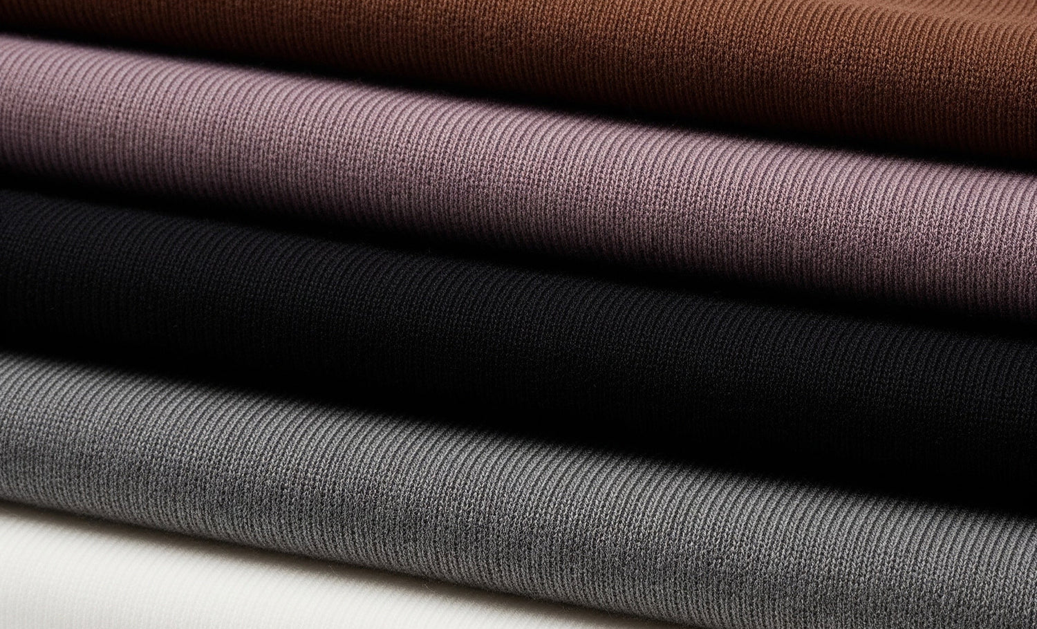 Stack of folded fabric swatches in brown, purple, black, and gray on a white background